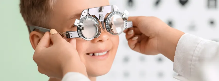 Bambino sorridente con l’occhiale di prova durante la visita oculistica